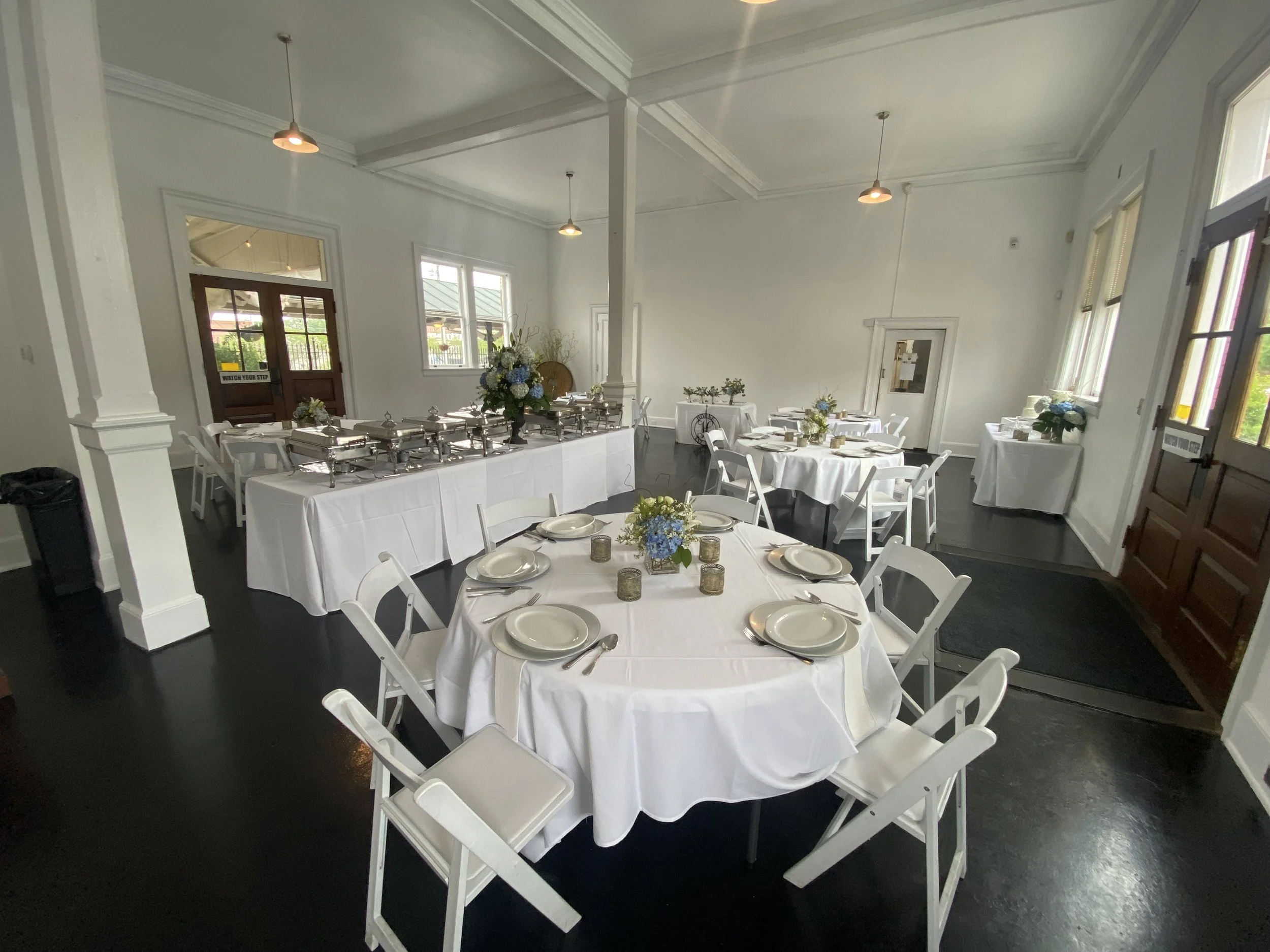 The Beauchamp Room with bright white walls, pendant lights, and round tables arranged for guests