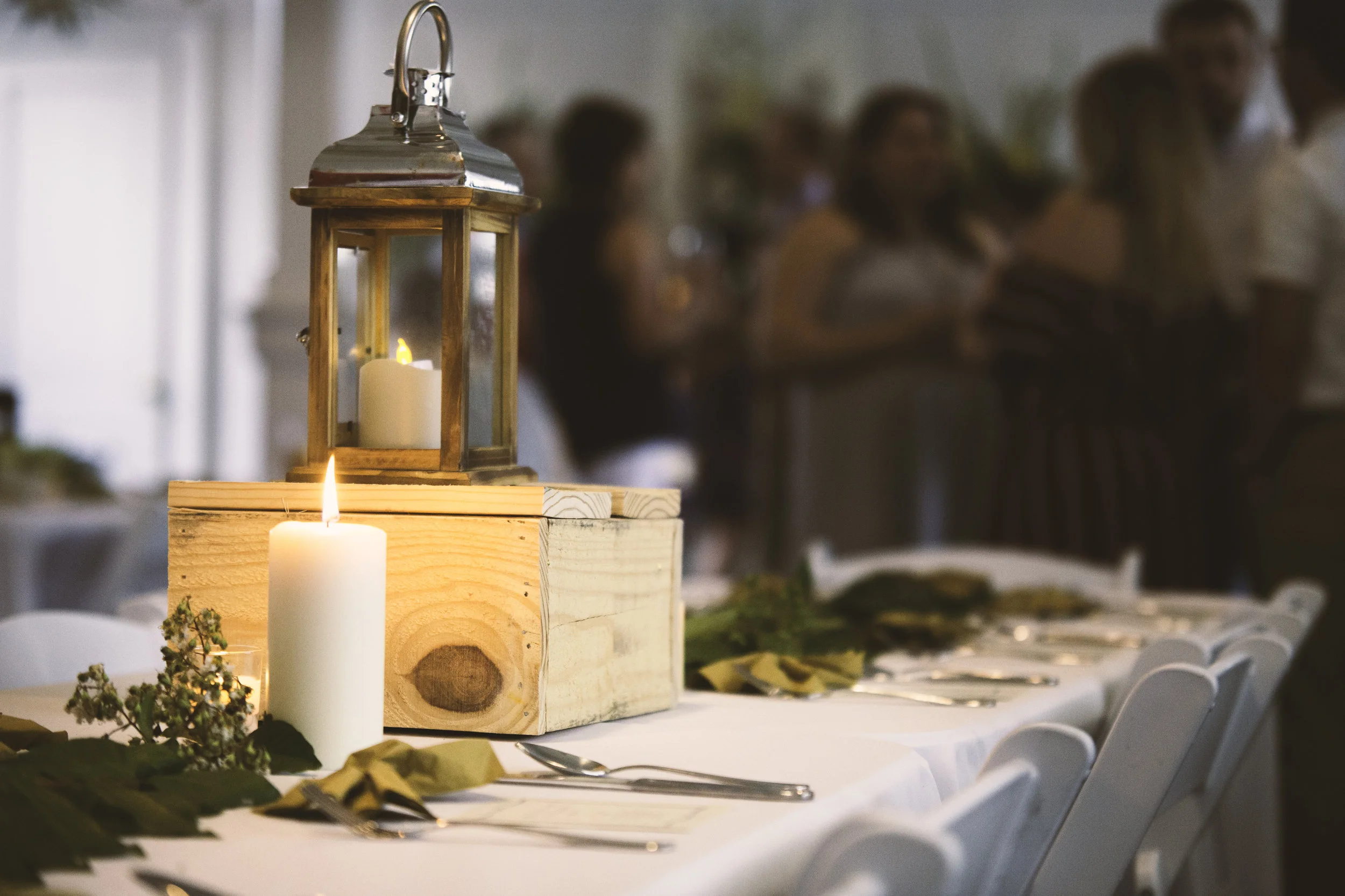 Elegant table centerpiece with lantern and greenery at a Sass! catered event